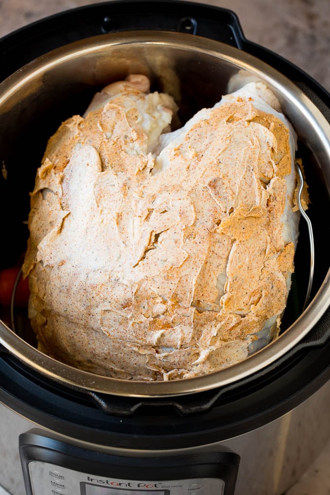 A butter coated turkey breast inside a pressure cooker.