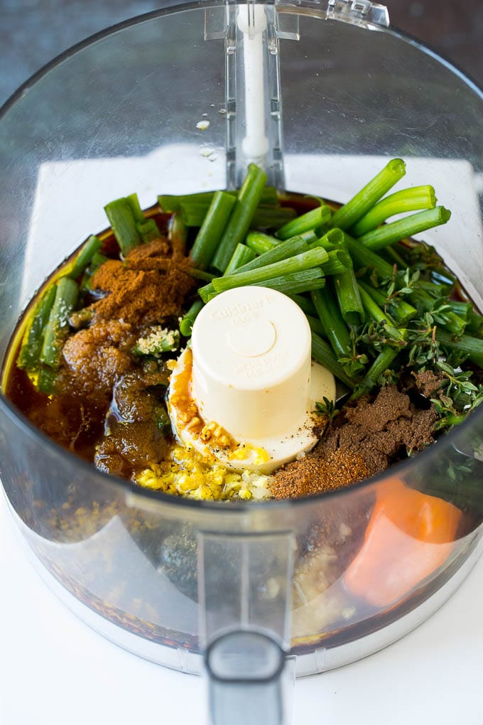 A food processor filled with herbs, garlic, olive oil and spices.