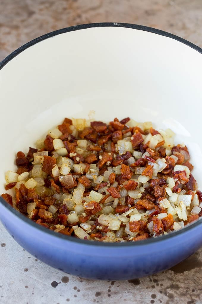 Cooked bacon and onions in a pot.