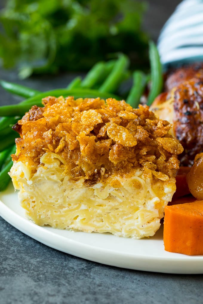 A slice of noodle kugel on a plate with chicken, sweet potatoes and green beans.