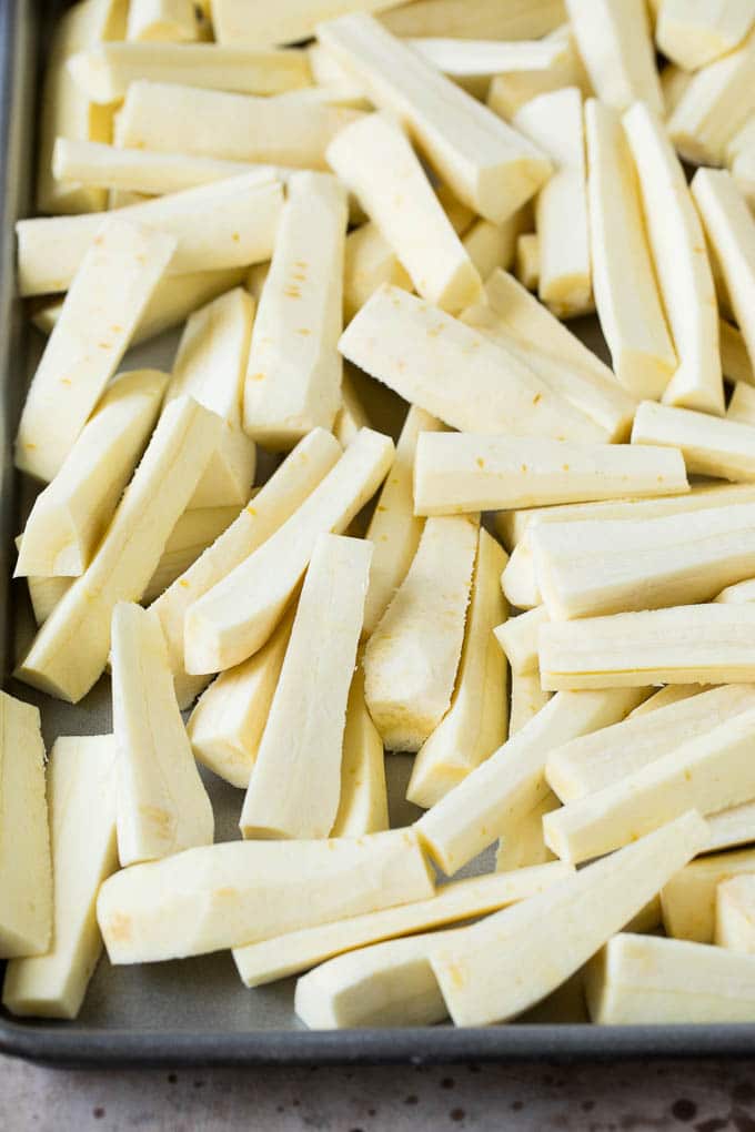 Parsnips cut into sticks on a sheet pan.