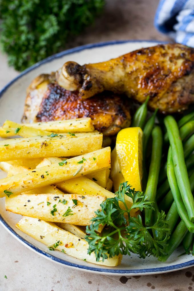 These roasted parsnips are coated in garlic, olive oil and herbs, then cooked in the oven until golden brown and tender. A quick and easy side dish option that pairs perfectly with chicken, beef and pork. A plate of chicken, green beans and roasted parsnips.