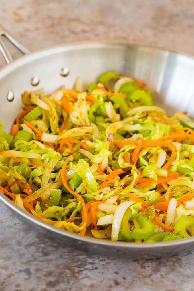 Sauteed cabbage, carrots and onions in a pan.