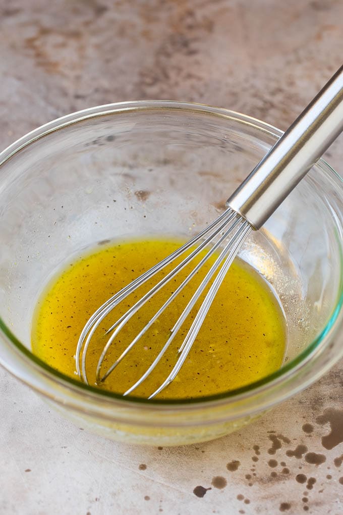 A bowl of salad dressing with a whisk in it.