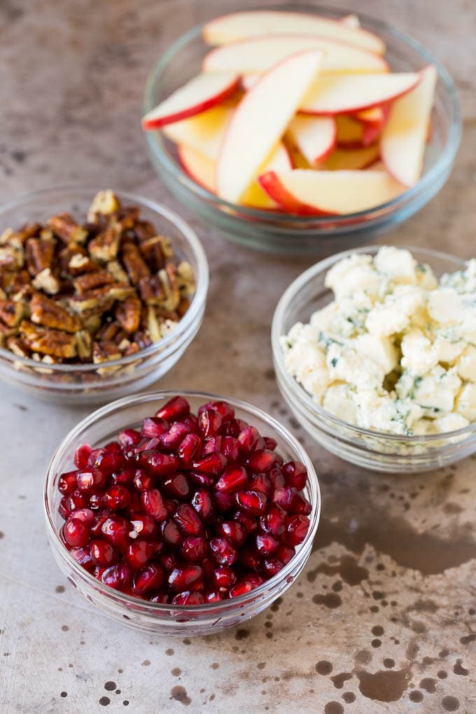 Bowls of cheese, pomegranate arils, apples and pecans.