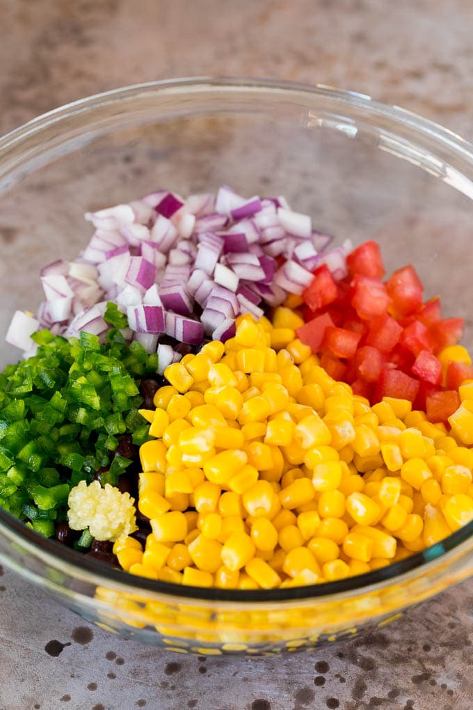 Corn, tomatoes, jalapeno and red onion in a bowl.