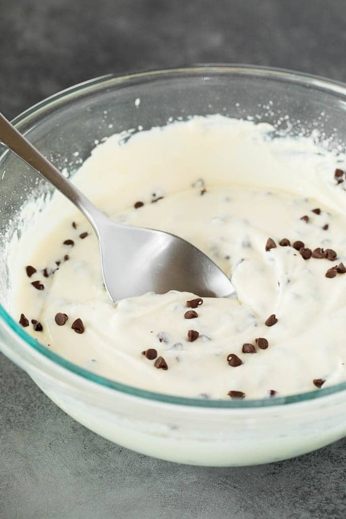 A glass bowl filled with a mixture of sweet Italian cheeses, powdered sugar and chocolate chips.