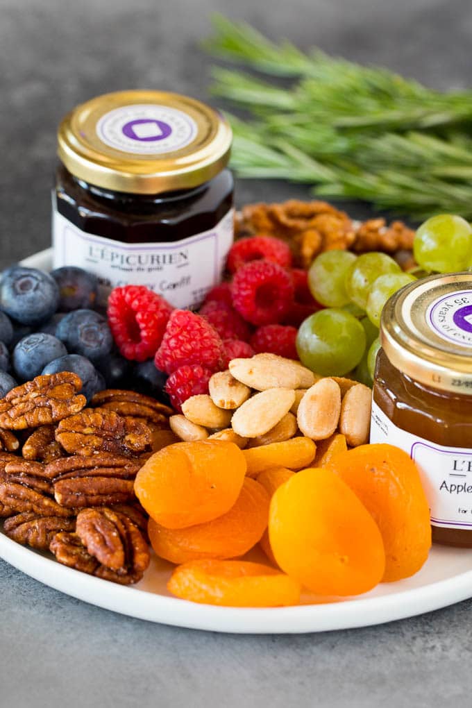 A plate with fresh and dried fruit, nuts and jam.