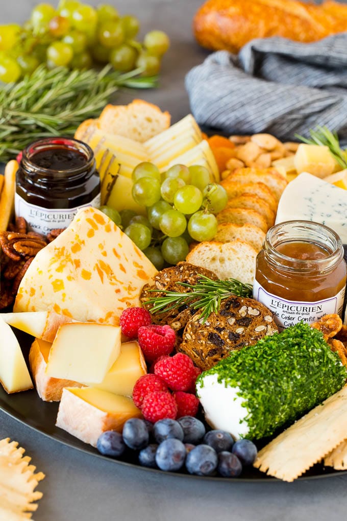 A cheese board with crackers, fruit, nuts and jam.