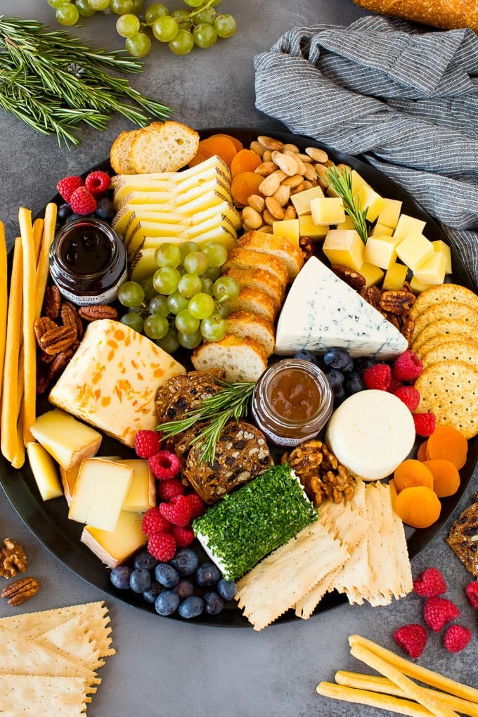 The best cheese board with assorted cheeses, bread, crackers, fruit and nuts on a large platter.