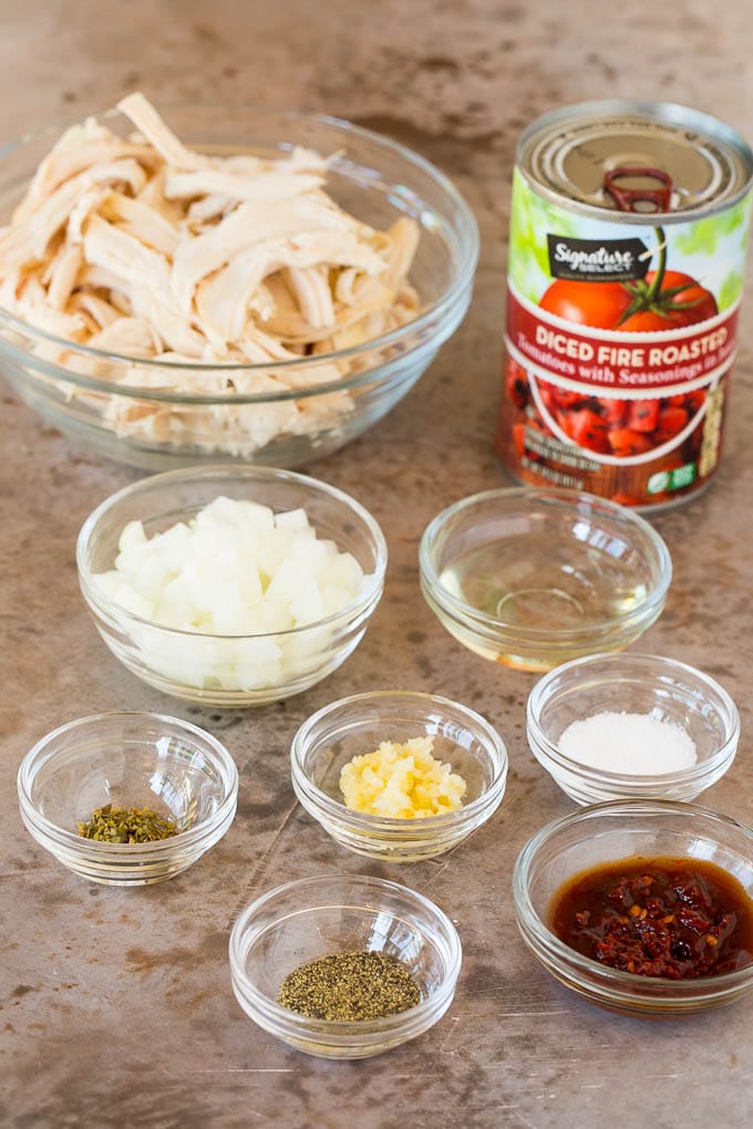 Bowls of ingredients such as chicken, spices, onions and garlic.