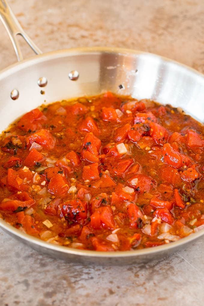 A pan of tomatoes, onions, garlic and herbs.