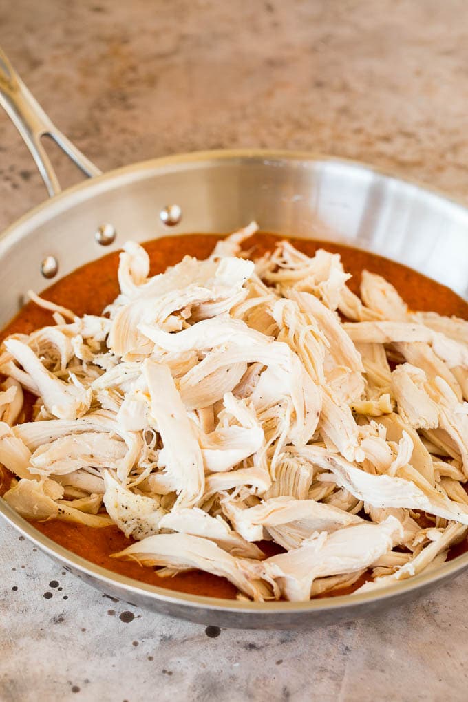 Shredded chicken in a pan of tomato sauce.