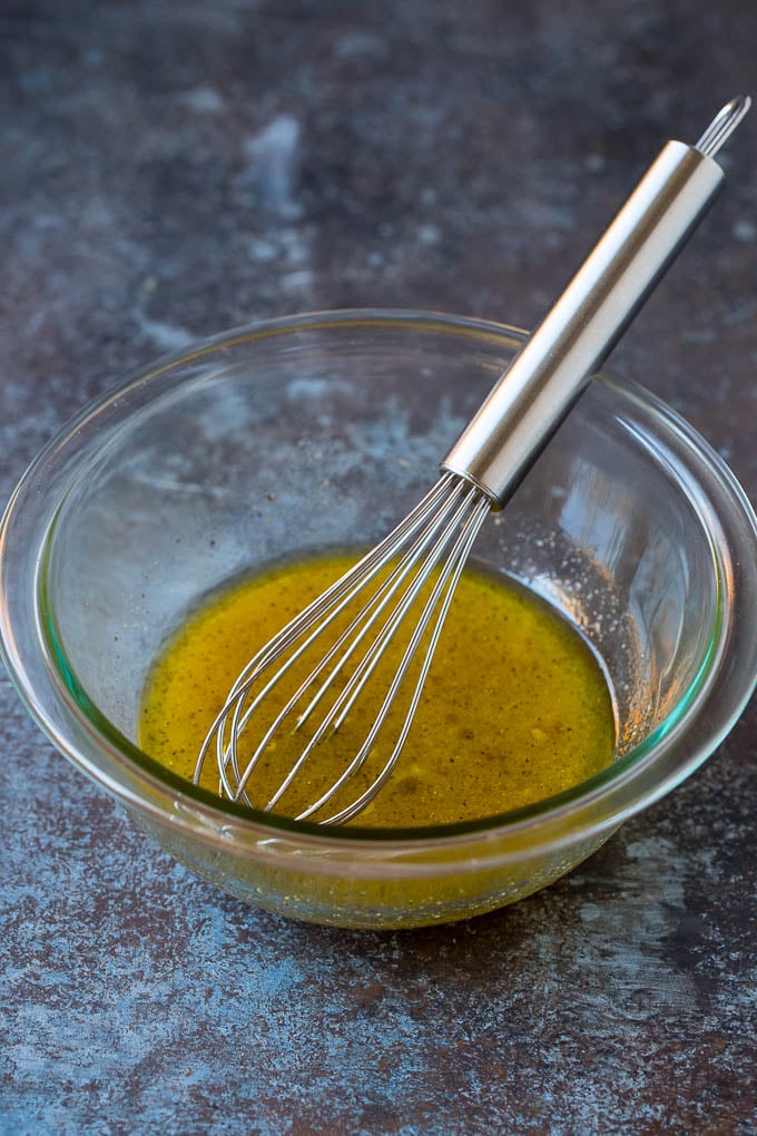 A bowl of homemade salad dressing with a whisk in it.