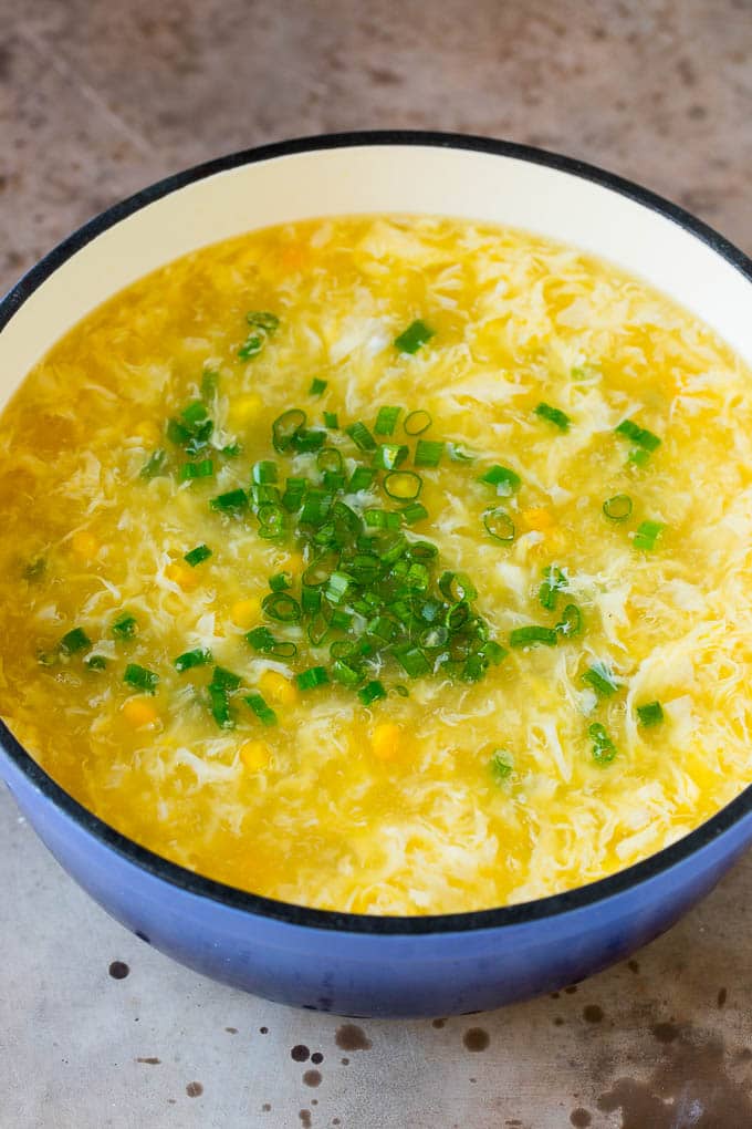 A pot of soup with corn and green onions stirred in.