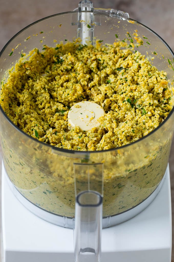 Ground up chickpeas, spices and herbs in the bowl of a food processor.