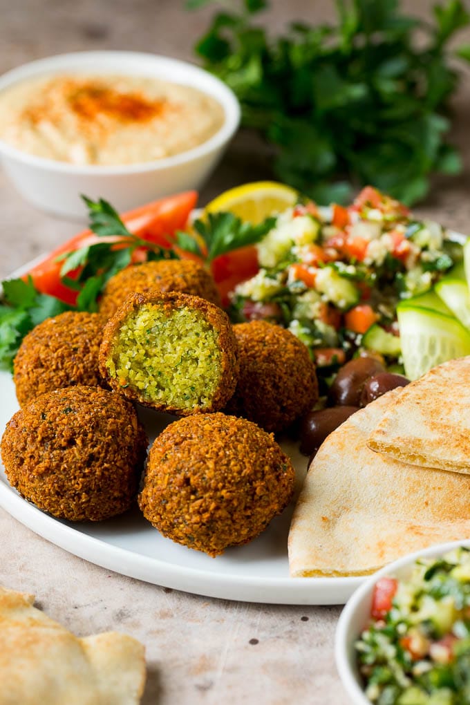 Falafel balls on a plate with olives, salad and pita bread.