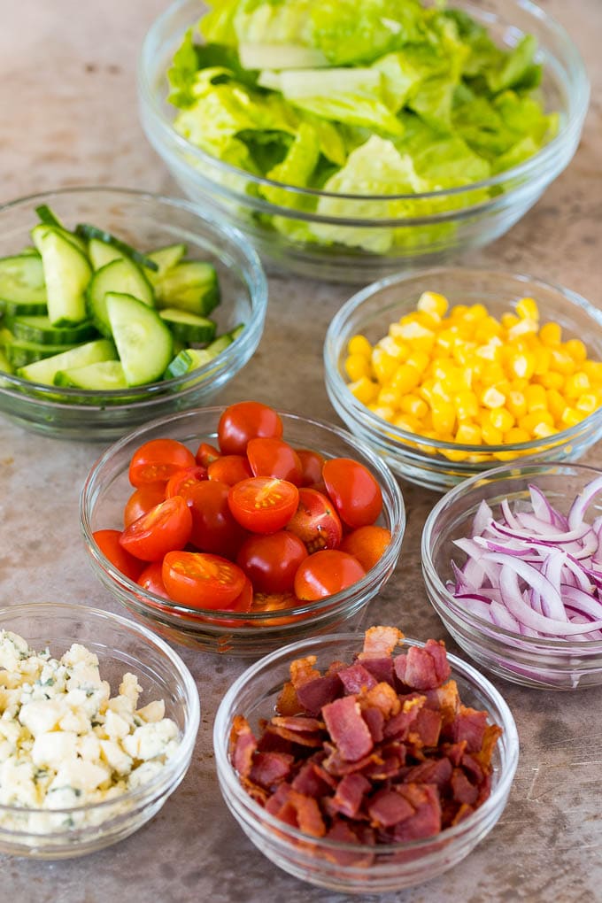 Bowls of lettuce, vegetables, bacon and blue cheese.