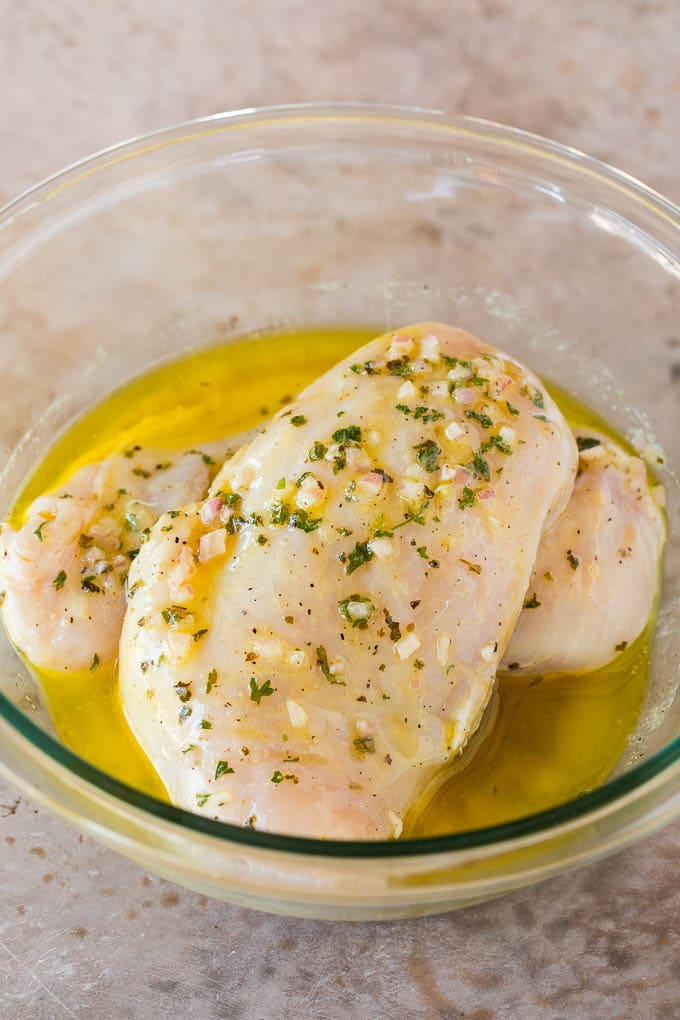 Chicken breasts in a bowl of marinade.