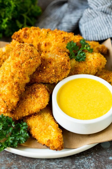A bowl of honey mustard sauce served with chicken fingers.