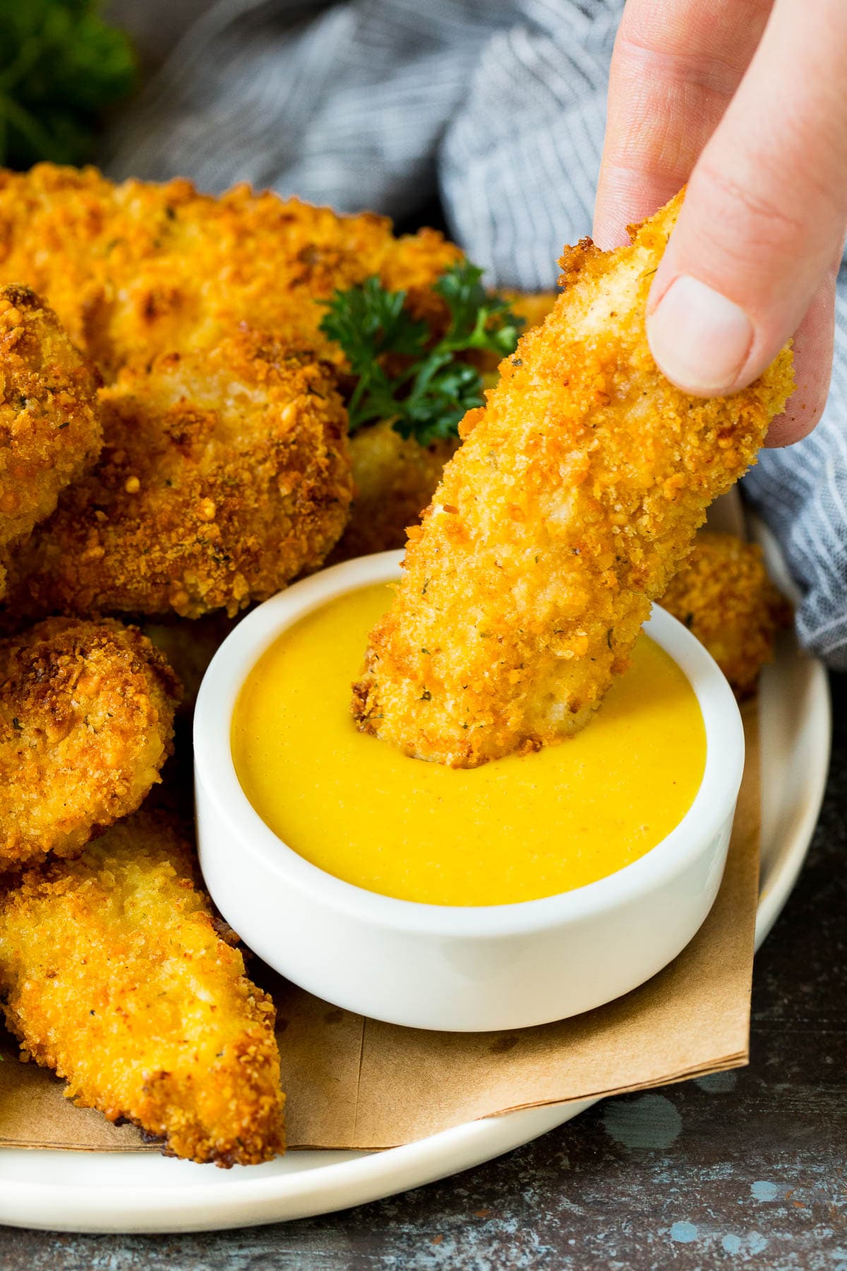 A chicken finger being dipped into honey mustard sauce.