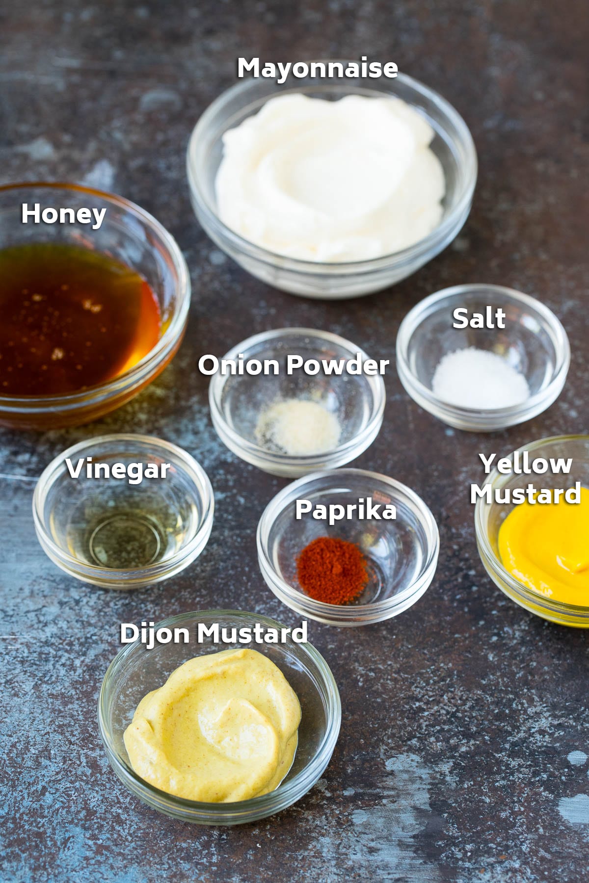 Bowls of mayonnaise, mustard, honey and seasonings.