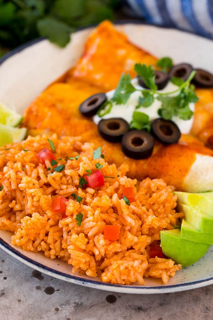 Mexican rice on a plate next to enchiladas.
