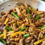 A pan of moo shu pork topped with sliced green onions.