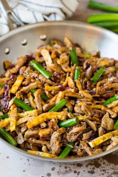 A pan of moo shu pork topped with sliced green onions.