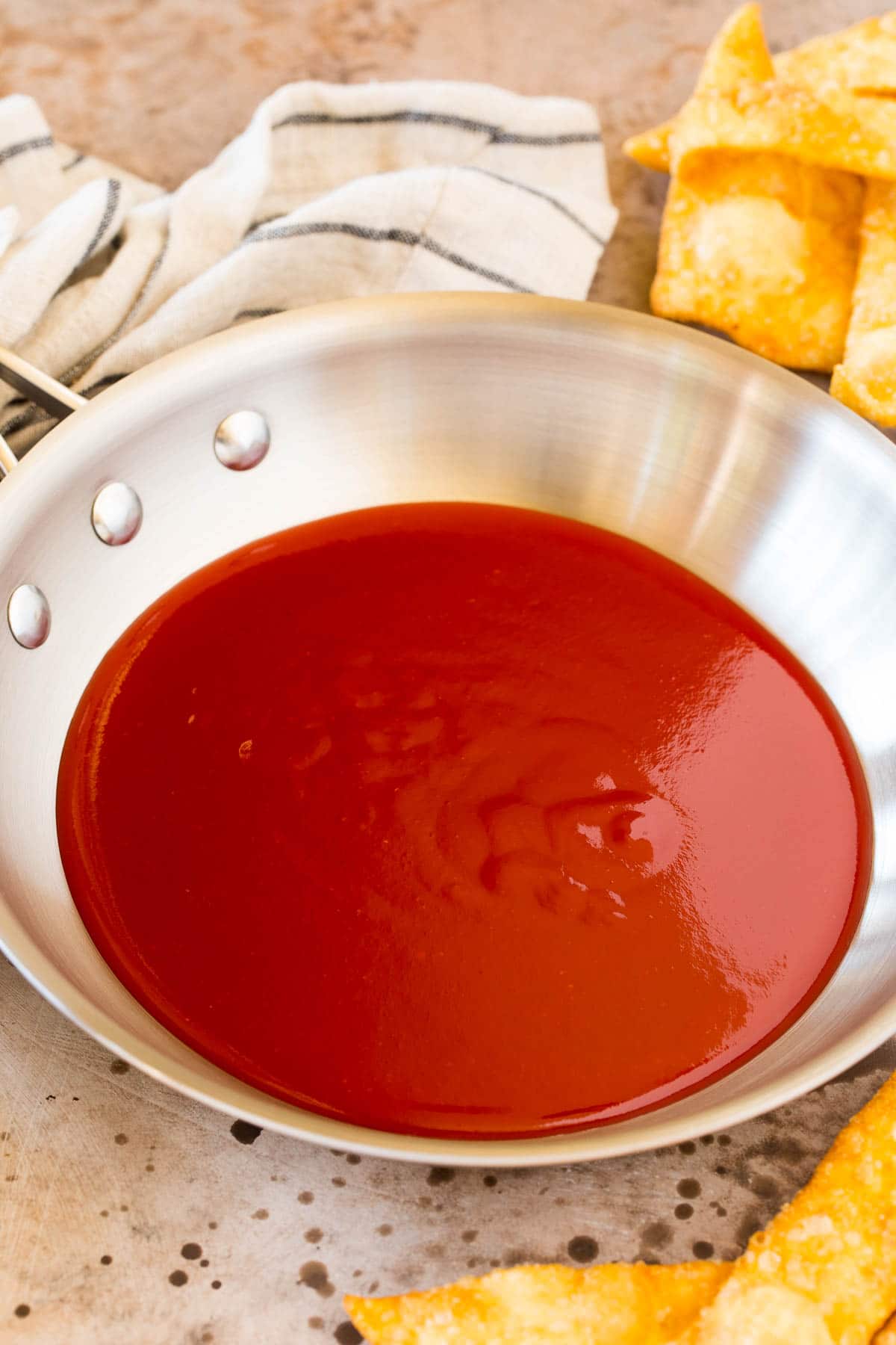 A pan of sauce with wontons surrounding it.
