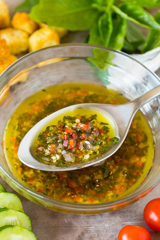 A bowl of homemade Italian dressing with a spoon in it.