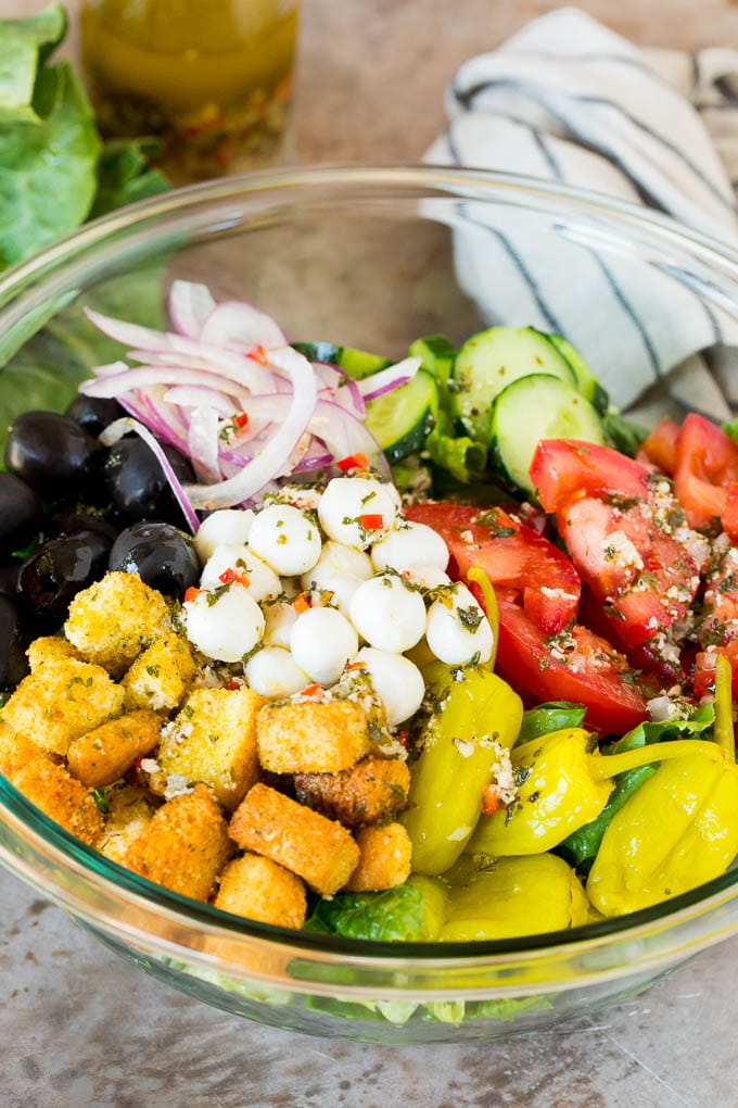 A bowl of salad with Italian dressing drizzled over the top.