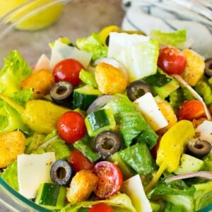 A bowl of Italian salad with cucumber, cheese and croutons.