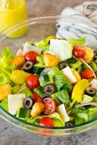 A bowl of Italian salad with cucumber, cheese and croutons.