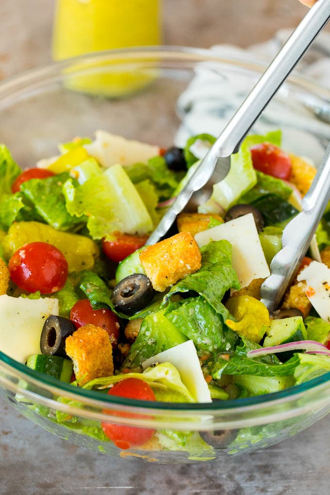 Tongs serving up a portion of Italian salad.