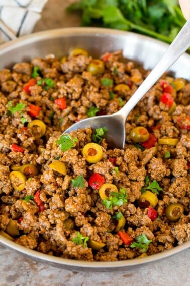 A pan of picadillo with a serving spoon in it.
