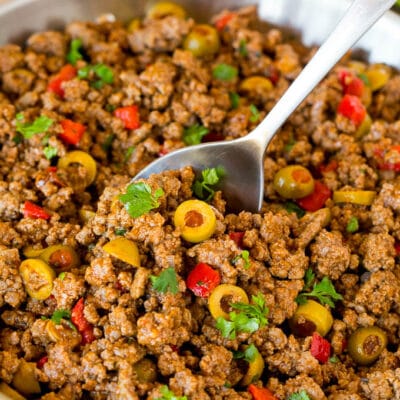 A pan of picadillo with a serving spoon in it.