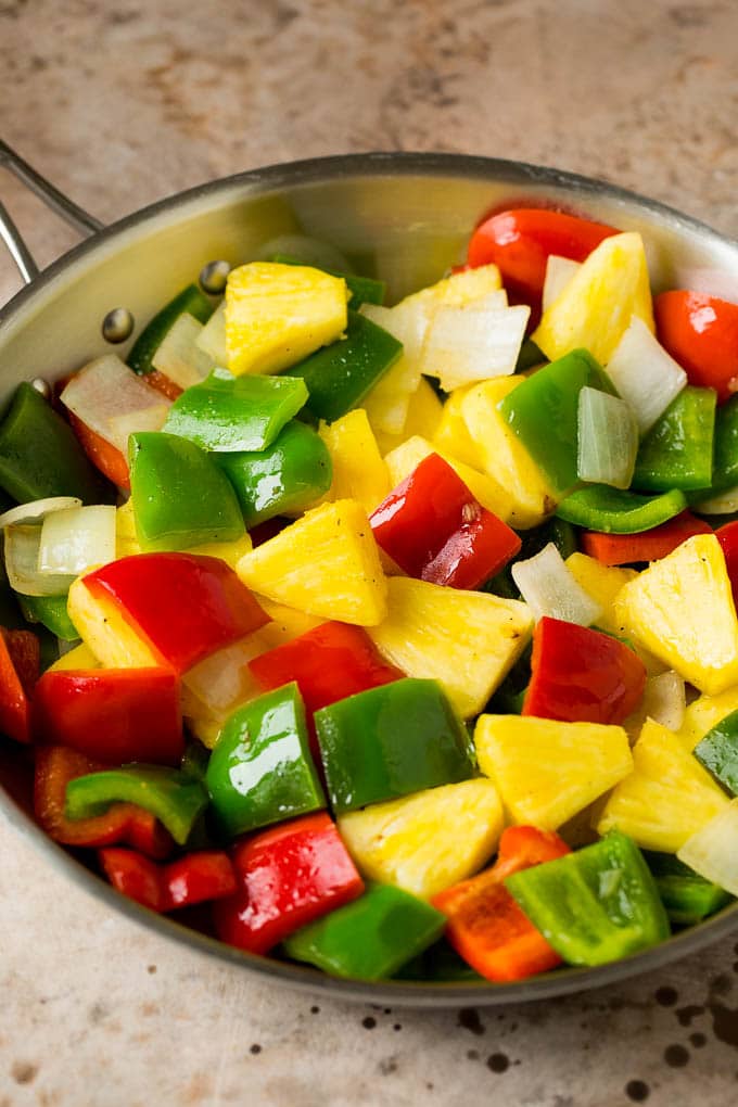 Pineapple, bell peppers and onions in a pan.