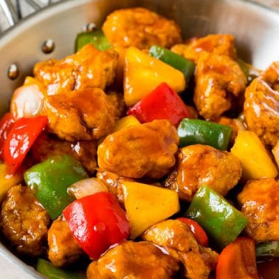 Sweet and sour pork with pineapple and bell peppers in a skillet.