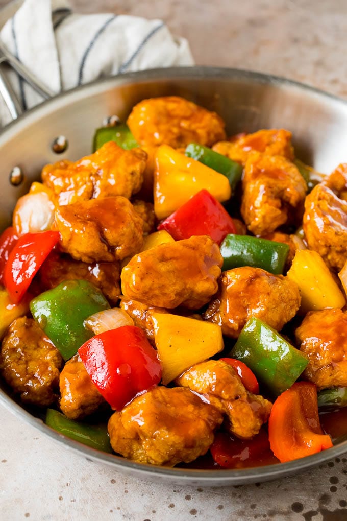 Sweet and sour pork with pineapple and bell peppers in a skillet.