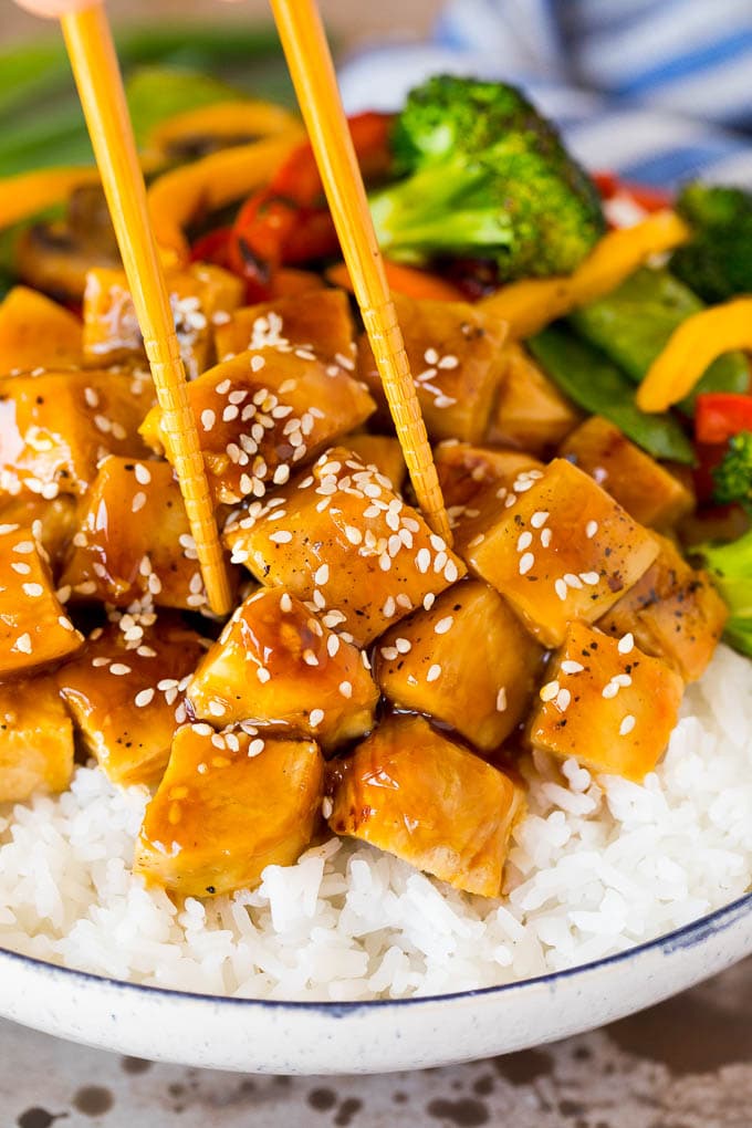 A set of chopsticks in a teriyaki chicken bowl.