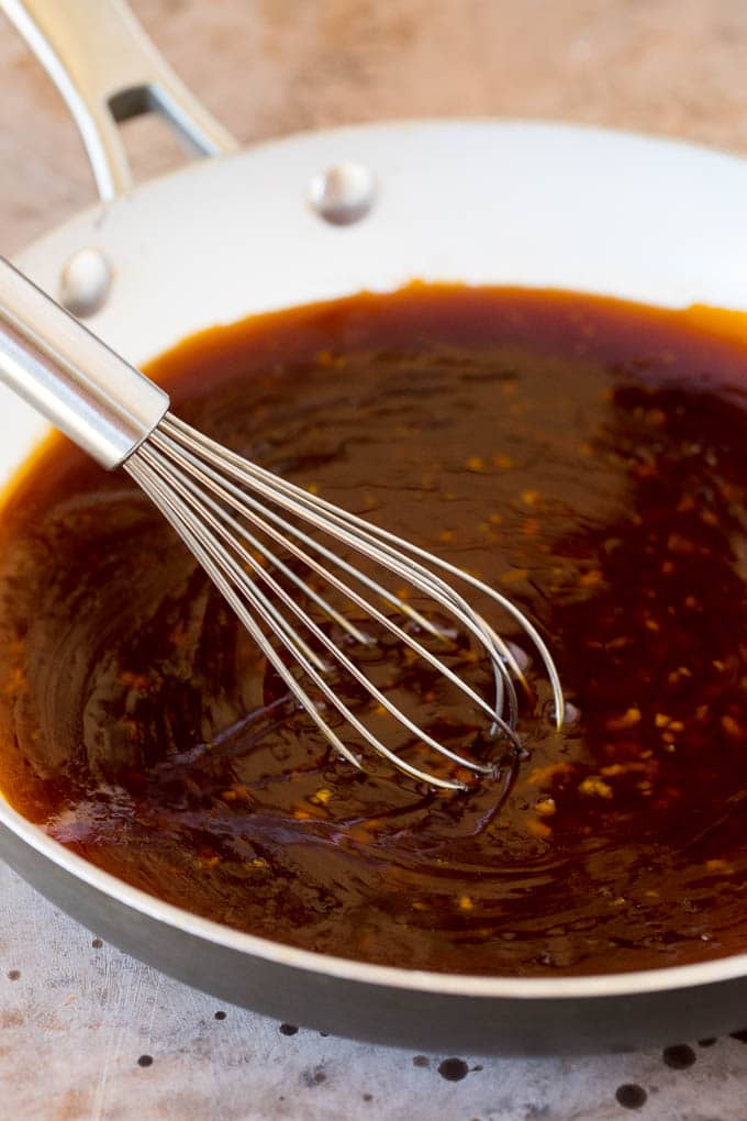 A whisk in a pan of teriyaki sauce.
