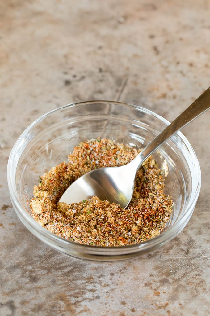 A bowl of chicken seasoning with a spoon in it.