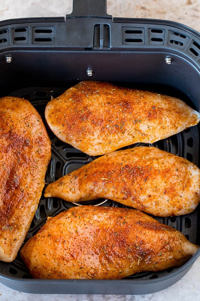 Seasoned chicken breasts inside an air fryer.