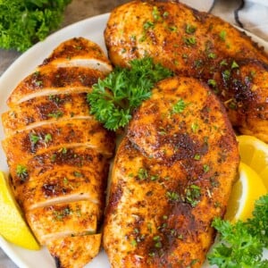 Air fryer chicken breast on a plate with lemon and parsley for garnish.