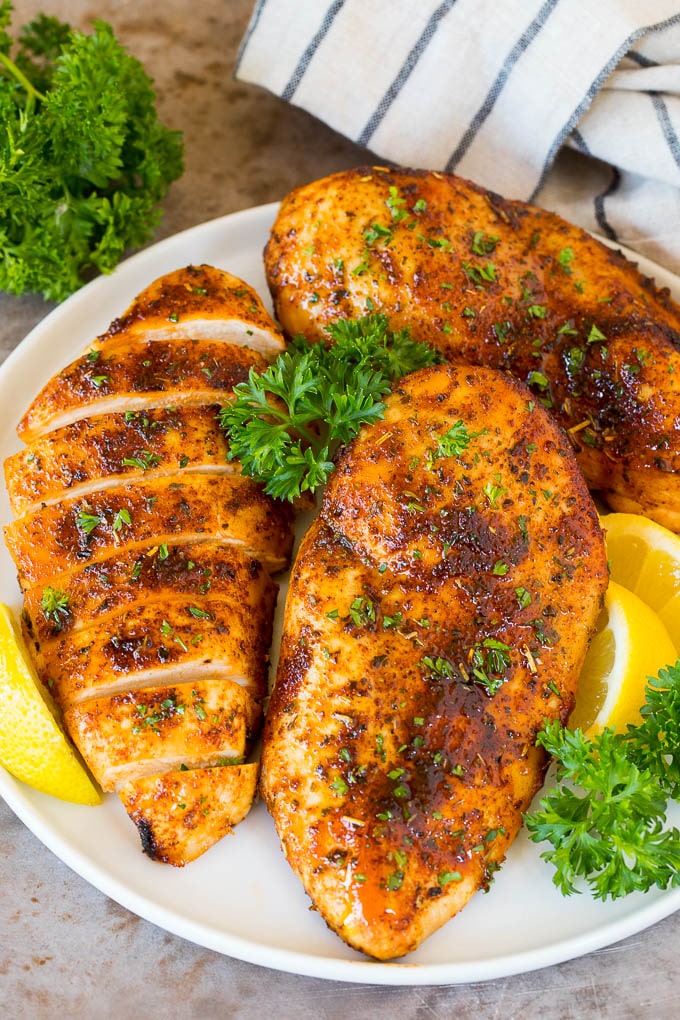 Air fryer chicken breast on a plate with lemon and parsley for garnish.