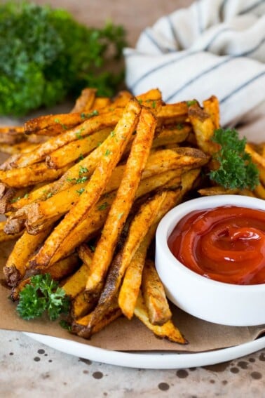 A plate of air fryer french fries garnished with parsley and served with ketchup.