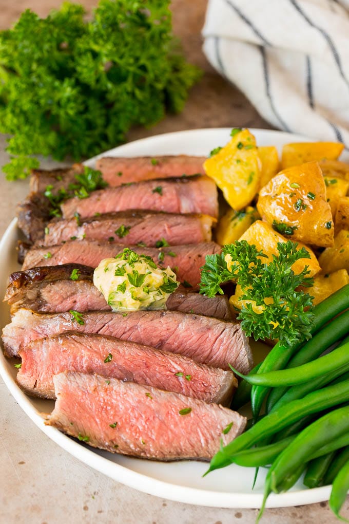 Sliced air fryer steak served with potatoes and green beans.