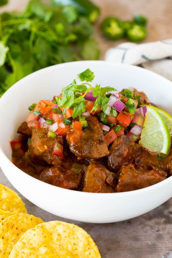 A bowl of carne guisada topped with pico de gallo.