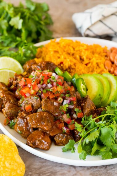 Carne guisada served with rice, beans and avocado.